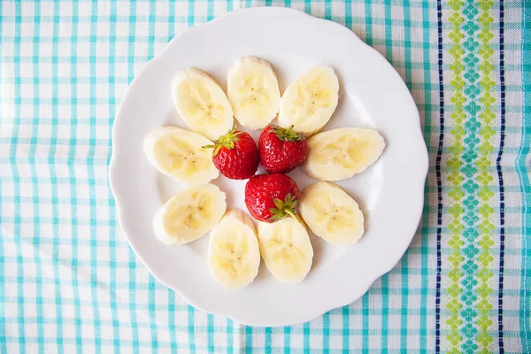 Банан і полуниця на білій тарілці і барвиста серветка — стокове фото