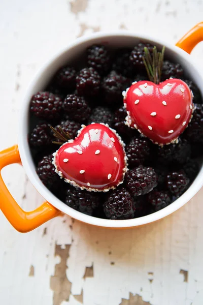 A full blackboy plate with a dessert in the form of a heart stands on a wooden background, close-up