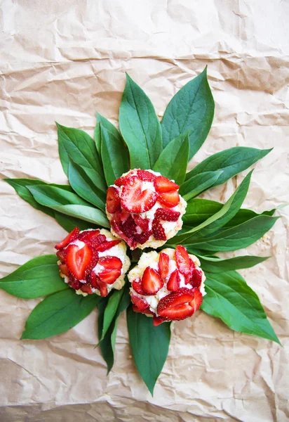 Schöne und helle Cupcakes mit Erdbeeren liegen auf grünen Blättern — Stockfoto