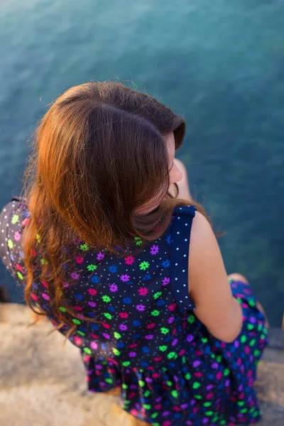 The girl in a beautiful dress is sitting on the pier. — Stock Photo, Image