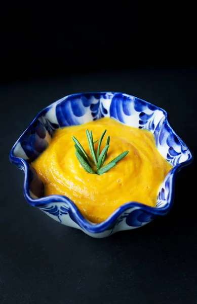 Pumpkin soup in a blue plate on a black background — Stock Photo, Image
