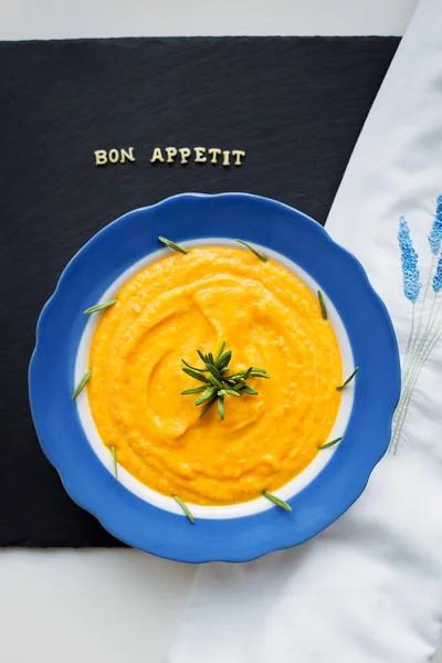 Pumpkin soup in a blue plate on a black background with a white cloth, close-up — Stock Photo, Image