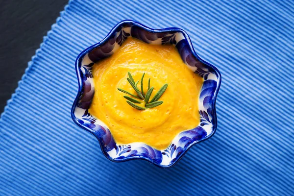 Pumpkin soup in a blue plate on a black background with a blue cloth, close-up — Stock Photo, Image