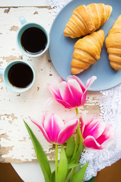 Coffee, croissants and three beautiful pink tulips on old white table — Stock Photo, Image