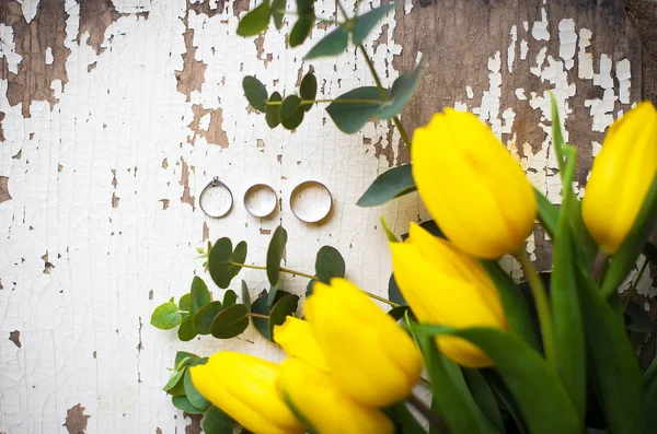 Anillos de boda con tulipanes amarillos sobre mesa blanca vieja —  Fotos de Stock