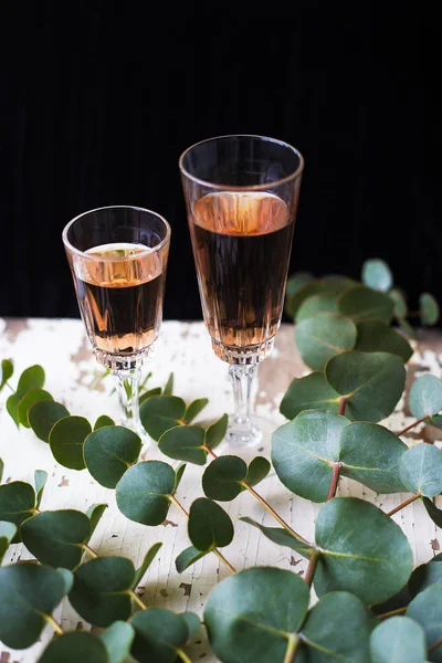 Ramas de eucalipto sobre una mesa vieja con una copa de vino de rosas — Foto de Stock