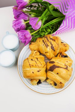 üç ay çöreği, iki bardak kahve masada ve güzel lale buketi