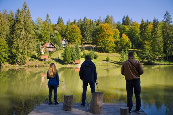 fishing friends on the lake in a beautiful autumn forest.