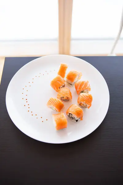 Sushi roll with salmon, philadelphia on a white plate on a black background top view. — Stock Photo, Image