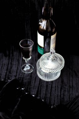 Tatlı yemekler, şişe ve siyah bir zemin üzerine kırmızı şarap.