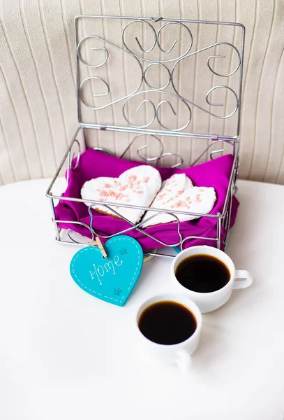 Cookies in a heart and two cups of coffee on the table that says home.