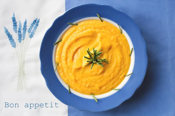 カボチャのスープを青皿に盛り付け ローズマリーをナプキンに花を添えて — ストック写真