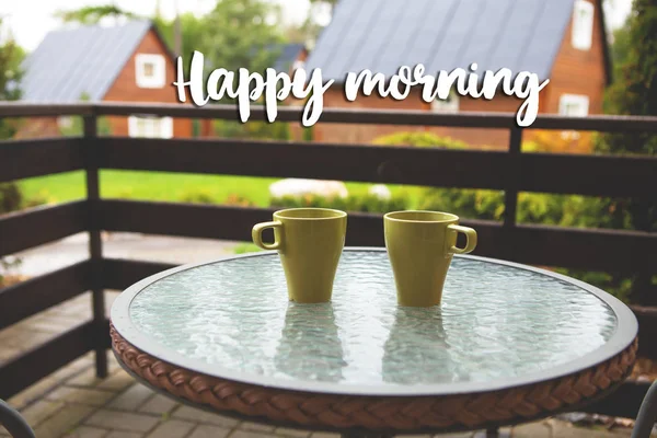 Twee kopjes koffie op de tafel op straat. Terras, vakantie, bergen, bos. Inscriptie Happy Morning. — Stockfoto