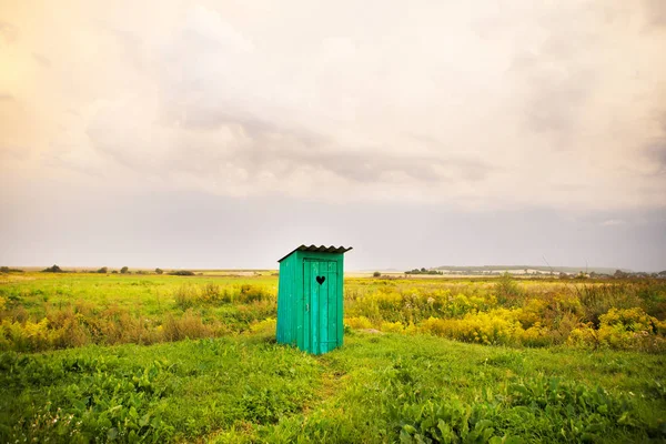 Holztoilette mit einem geschnitzten Fenster in Herzform, ein offenes Feld — Stockfoto