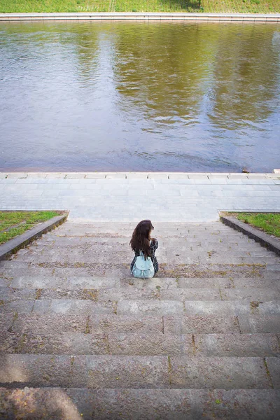 Piękna dziewczyna siedzi i patrzy na rzekę Wilno — Zdjęcie stockowe