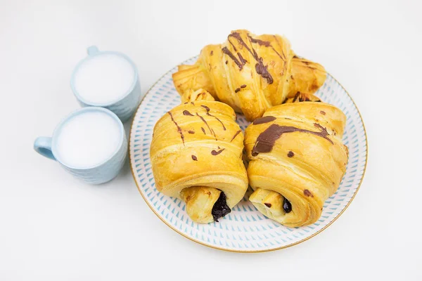 Three freshly baked croissants on a white ceramic plate, two cups of coffee — Stock Photo, Image