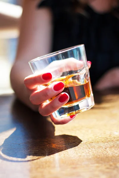 kız bir kafede oturuyor ve bir bardak viski tutuyor