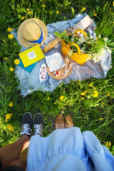 Una coppia amorevole, un picnic sulla natura, un tappeto su cui si trova cibo-formaggio, baguette, torta, fragola — Foto Stock