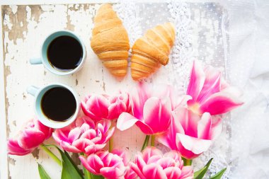 güzel bir fincan kahve, kruvasan ve pembe laleler eski beyaz masaya yakın çekim