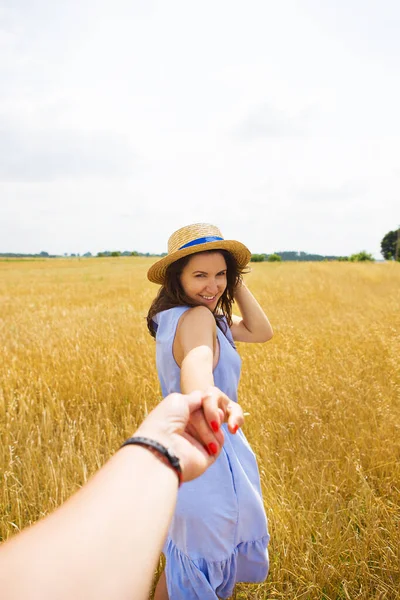 Una chica en un vestido azul está de pie con su espalda en un campo de trigo — Foto de Stock