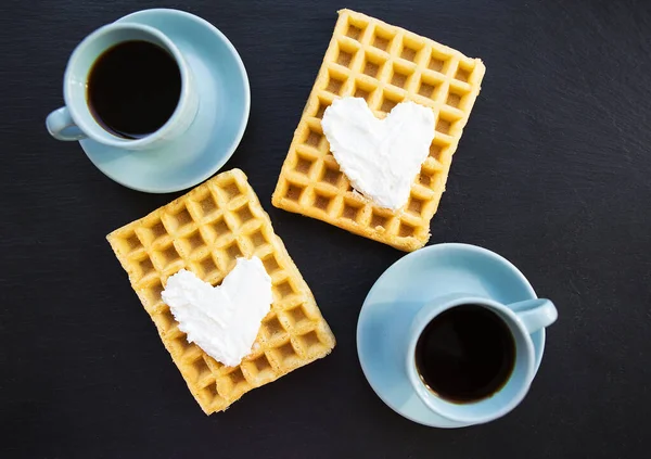 Köstliche belgische Waffeln mit Sahne auf schwarzem Hintergrund und zwei Tassen Kaffee. — Stockfoto