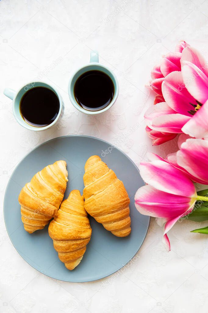 two cups of coffee, croissants and a bouquet of pink tulips, beautiful morning