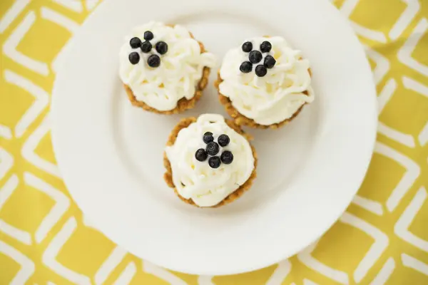 Hausgemachte Muffins mit Blaubeeren, Sahne und frischen Beeren auf gelber Serviette — Stockfoto