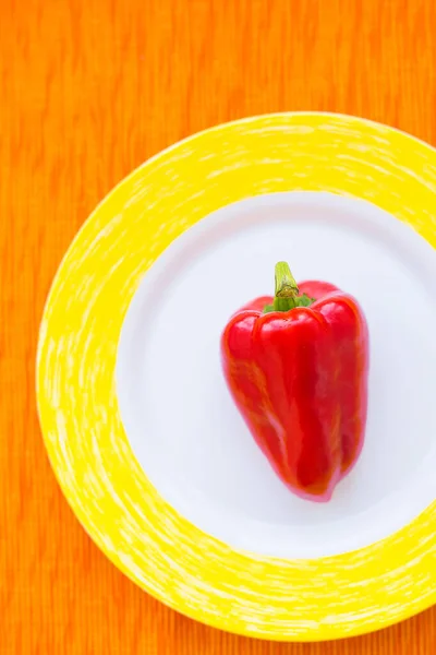 Un pimiento rojo en un plato colorido primer plano —  Fotos de Stock