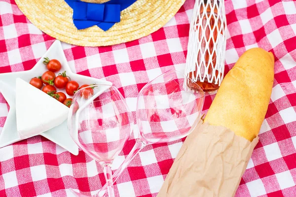hat, glasses, bread and cheese on red tablecloth