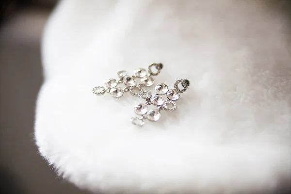 Bride earrings lie on white cape closeup — Stock Photo, Image