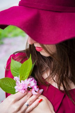 Kırmızı elbiseli kız elinde sakura tutuyor.