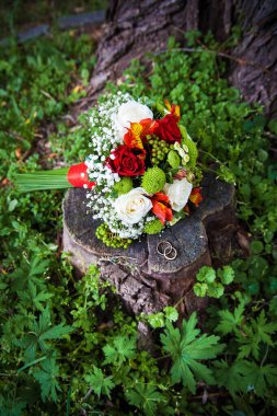 Yüzükler ve kütüğün üzerindeki güzel düğün buketi.