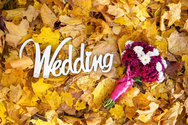 La palabra boda del árbol sobre las hojas amarillas y el ramo de la novia —  Fotos de Stock