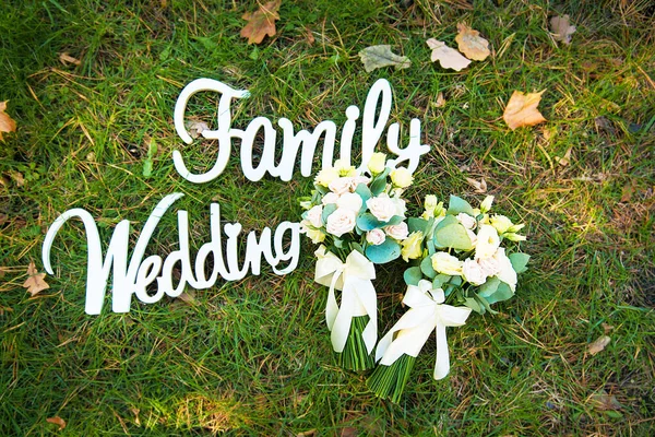 Η λέξη γάμος και η οικογένεια από ένα δέντρο σε πράσινο γρασίδι και νυφικό μπουκέτο — Φωτογραφία Αρχείου