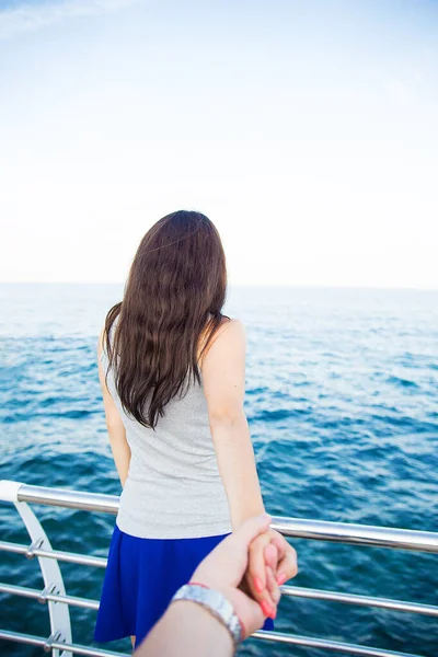 Woman sitting at the harbour on the quay with her back to the camera looking out at moored boats, shallow dof — Stock Photo, Image