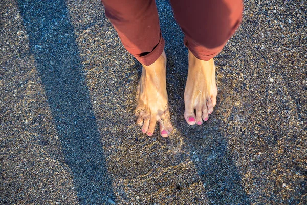 Kobieta stojąca na plaży z falą morza — Zdjęcie stockowe