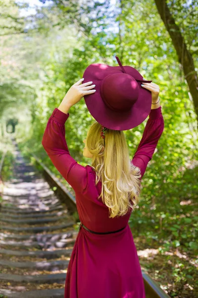 Schönes Mädchen im Kirschkleid mit Hut im Wald — Stockfoto