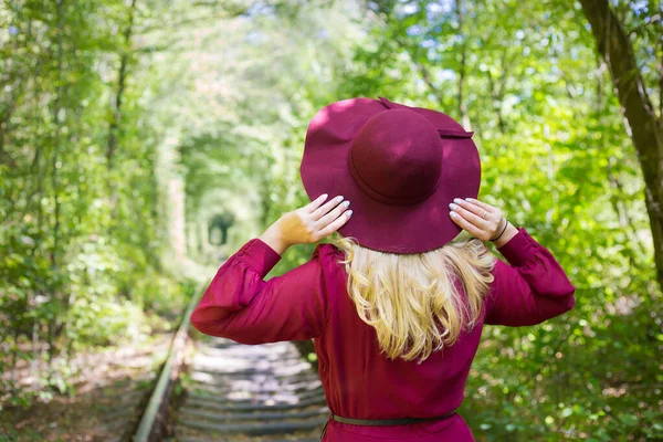 Bella ragazza in abito di ciliegia con un cappello nel bosco. — Foto Stock