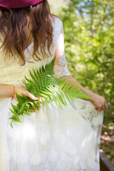 Dívka v bílých šatech, drží zelené kapradí listy v lese — Stock fotografie