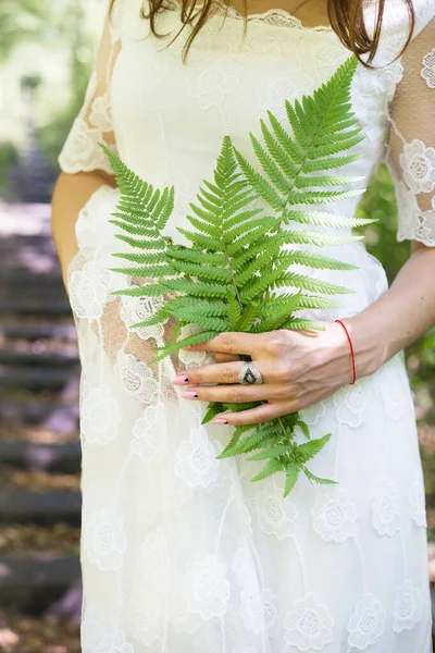 Lány fehér ruhában, kezében egy zöld páfrány levelek az erdőben — Stock Fotó