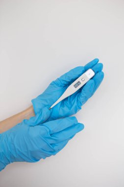 Doktorun elinde mavi lateks eldiven var. Mavi arka planda hastanın vücut sıcaklığını gösteren bir termometre var. Grip, hastalık konsepti