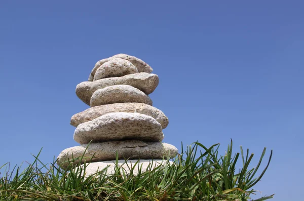 Pile of stones in grass against  a bright blue sky