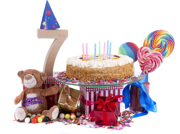 紙のパーティの帽子 赤いハートや紙吹雪と甘いケーキのろうそくの下にプレゼントとカラフルなスタジオの設定で年齢の数 — ストック写真