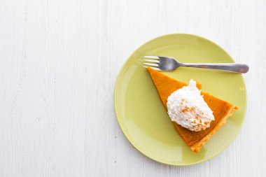 Beyaz ahşap zemin üzerine krem şanti ile kabak pasta dilim 