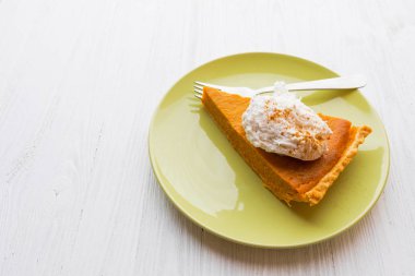 Beyaz ahşap zemin üzerine krem şanti ile kabak pasta dilim 