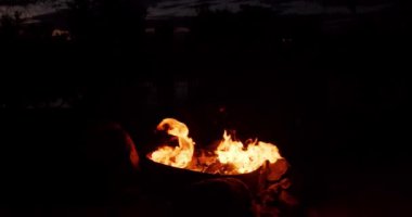 Gece kamp ateşinin alevleri, siyah arka planda yanan alevlerin yakın çekimi.