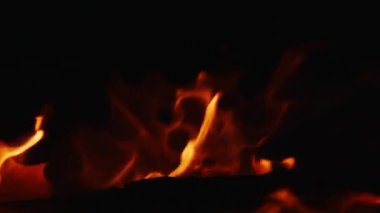 Gece kamp ateşinin alevleri, siyah arka planda yanan alevlerin yakın çekimi.