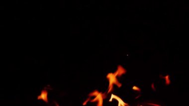 Gece kamp ateşinin alevleri, siyah arka planda yanan alevlerin yakın çekimi.