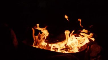 Gece kamp ateşinin alevleri, siyah arka planda yanan alevlerin yakın çekimi.