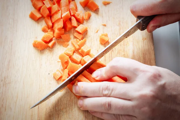 Woman hands chopping carrot on wooden board — Stock Photo, Image
